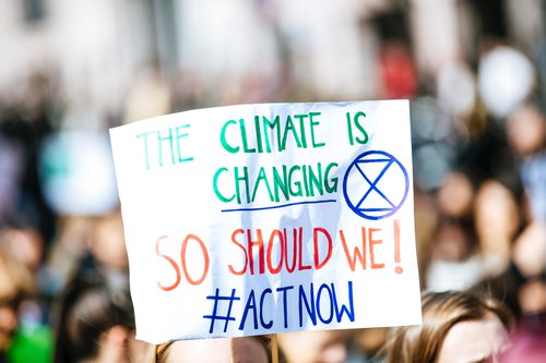 Protest sign that reads, " The Climate is Changing So Should We! #ACTNOW"