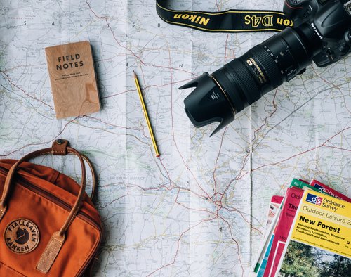 Paper map with Nikon camera, notebook, pencil, purse, and guidebooks laying on top.