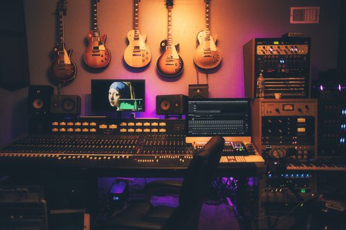 Music studio with a sound board on the desk and five guitars hanging on the wall