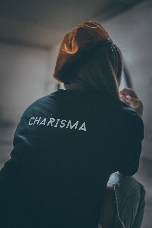 Person sitting facing away from the camera, with "CHARISMA" on their shirt