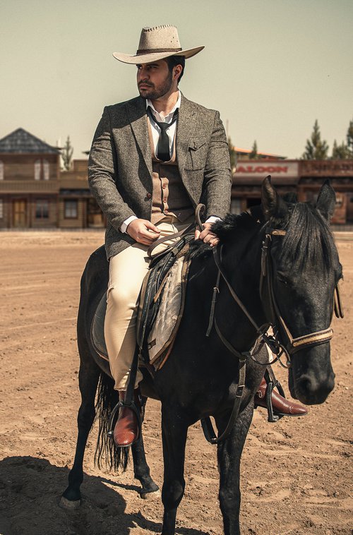 Man in a business suit and cowboy hat on a horse.