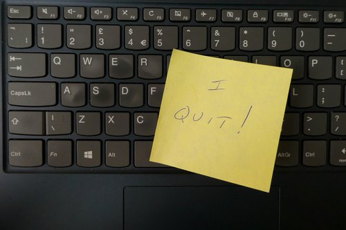 Yellow post-it note that reads "I QUIT!" on a black keyboard