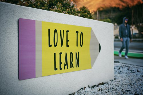 Wooden sign shaped like a pencil with the words, "Love to Learn."
